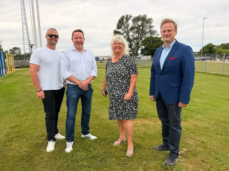 Representanter ifrån kommunstyrelsen samt Hässleholms HIF ler står på området där det är tänkt att byggas en ny mötesplats.