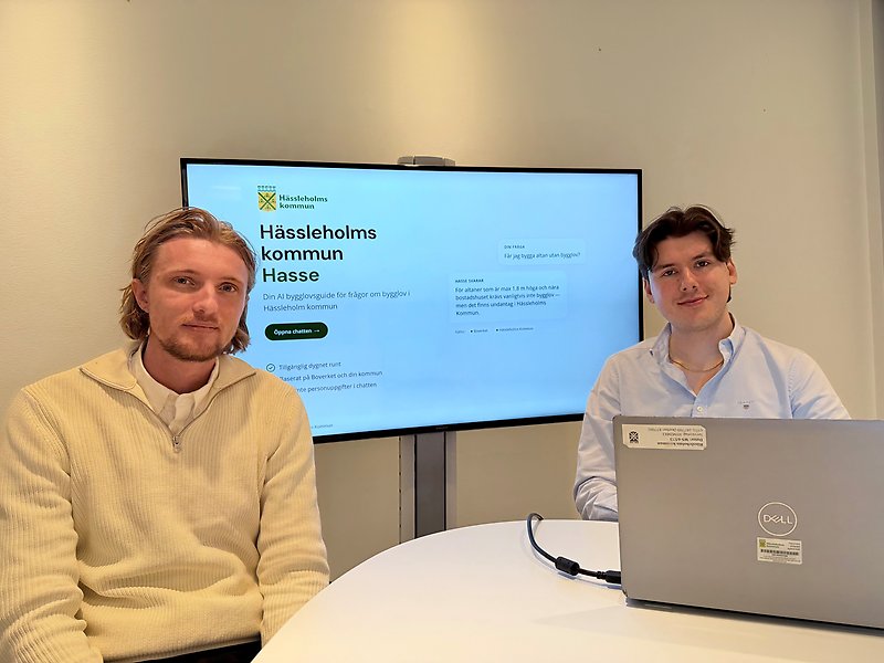 Byggnadsinspektör Noah och GIS-utvecklare David framför en TV-skärm som visar AI-assistenten Hasse.
